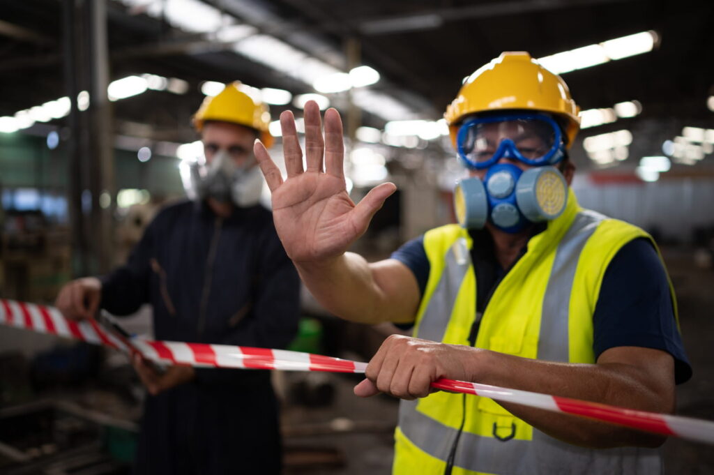 A worker in protective gear blocking access to a site in a facility.