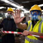 A worker in protective gear blocking access to a site in a facility.